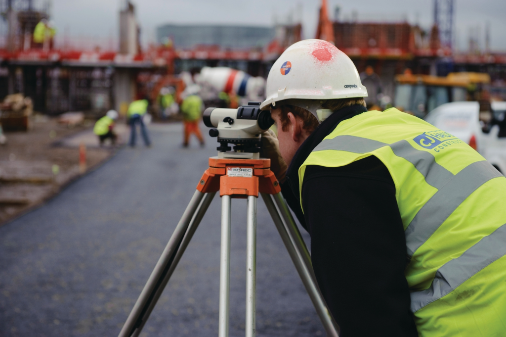 Persona en un sitio de construcción utilizando un instrumento de topografía.